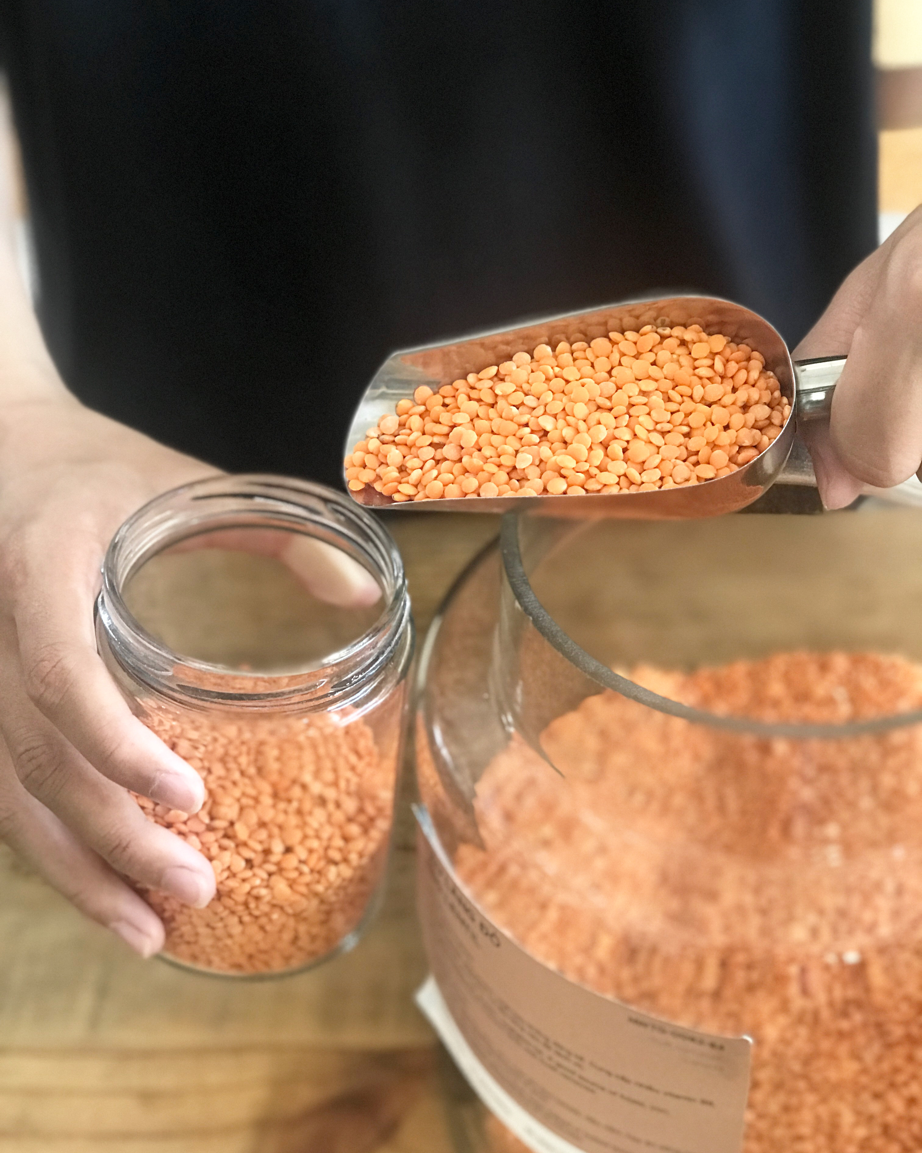 Scooping red lentils into a customer's jar